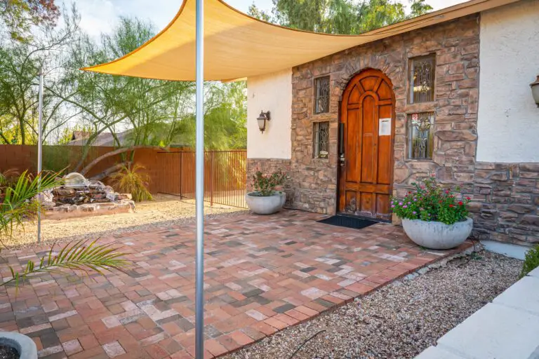 A brick patio with a yellow tent extension from the roof.