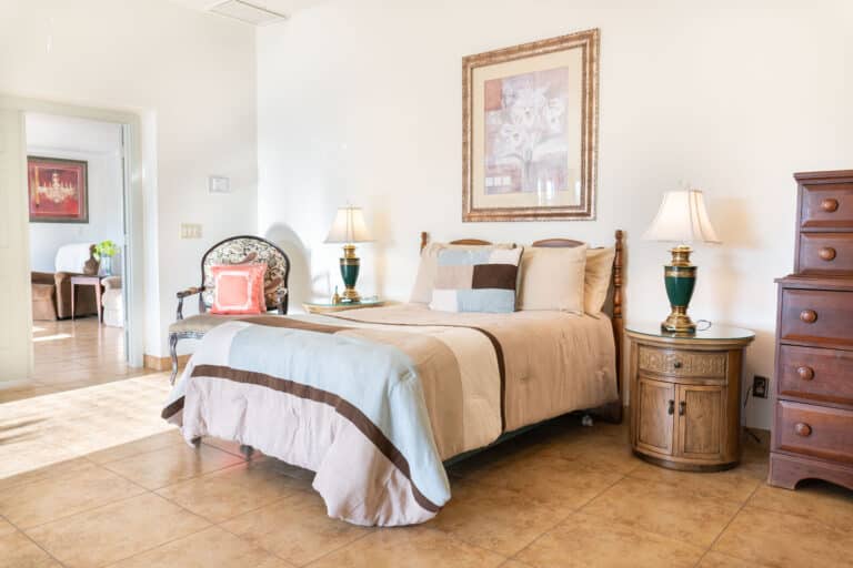 A bedroom with a bed, lamps and cabinets.