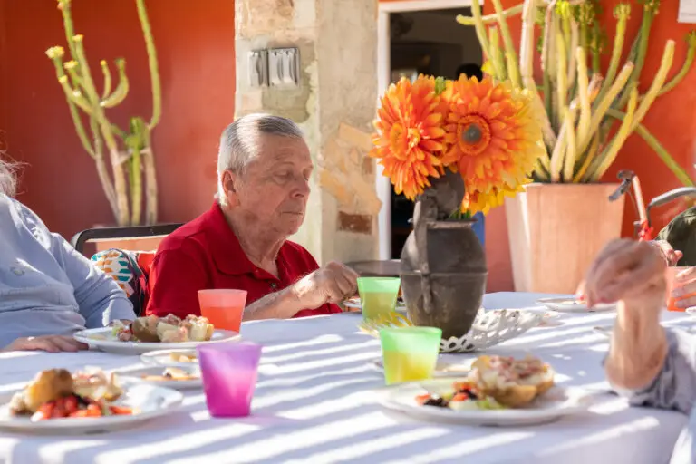 A senior sitting at a table with food and drinks
